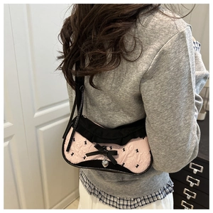Détail du sac bandoulière rose et noir avec volants, nœud et pendentif cœur