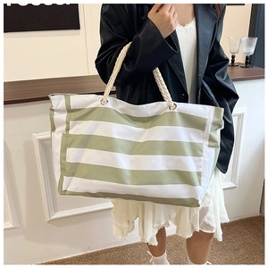 Detail of the green striped canvas tote bag featuring thick rope handles and metal eyelets