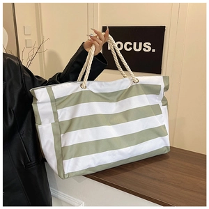 Detail of green and white striped oversized beach tote with white rope handles for travel