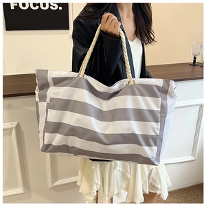 Close-up of grey and white striped canvas tote bag with thick rope handles and metal eyelets
