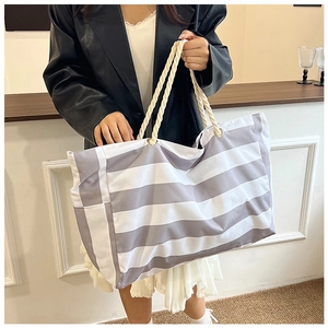 Detail of large striped canvas beach bag with sturdy rope handles and metal eyelets