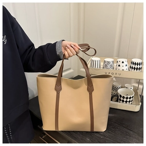 Dettaglio di una grande borsa tote minimalista in pelle PU beige con manici marroni chic