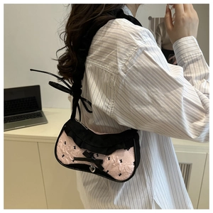 Détail du sac à bandoulière à carreaux roses avec nœud noir et pendentif cœur