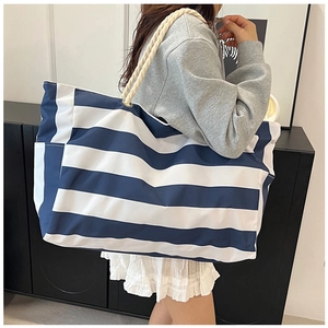 Close-up of striped canvas beach tote bag with thick rope handles on person