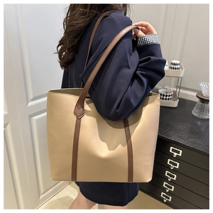 Dettaglio di una borsa tote in pelle kaki e marrone indossata da una modella in interni