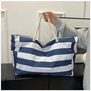 Close-up of blue and white striped canvas beach bag with thick rope handles and metal eyelets
