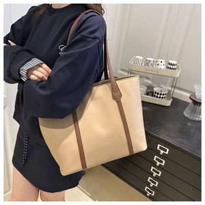 Vista dettagliata di una grande borsa tote beige con manici marroni sulla spalla