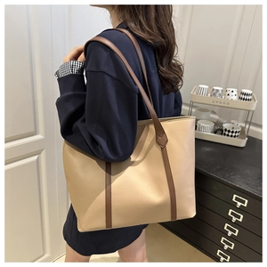 Vista laterale di una borsa tote grande bicolore beige e marrone indossata da una modella