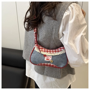 Détail du sac à épaule en jean avec bordure vichy rouge et écusson cerise sur le mannequin