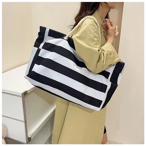 Detail of large striped tote bag with rope handles shown on a model in a room