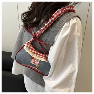Détail du sac bandoulière en jean avec bordure vichy rouge et écusson cerise