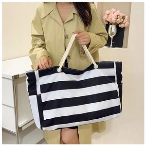 Detailed shot of large striped canvas tote bag with thick white rope handles and metal eyelets