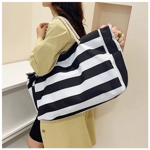 Detail of large striped canvas tote bag with nautical rope handles for women travel