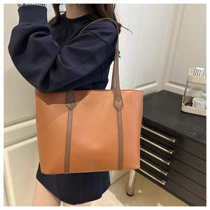 Borsa tote in pelle marrone abbinata a felpa blu navy in un ambiente interno accogliente