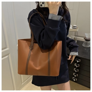 Dettaglio di una grande borsa tote marrone con spalline a contrasto su un modello