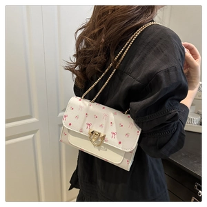 Detailed side view of white floral mini bag with pink bows and golden chain strap