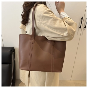 Vista dettagliata della grande borsa tote in ecopelle marrone indossata da una modella
