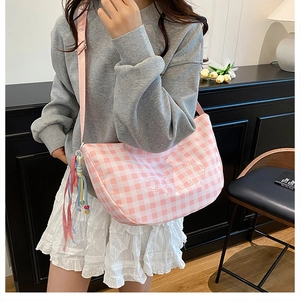 Detail of pink gingham half-moon bag with heart embroidery and colorful fringe charm