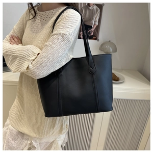 Dettaglio della borsa tote nera minimalista con cuciture decorative a freccia e capienza