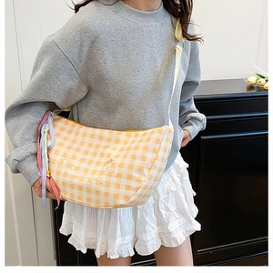 Detail of yellow checkered moon bag with embroidered bear heart pattern and ribbon