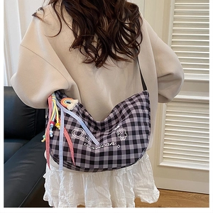 Detail of checkered crossbody bag with rainbow charm and cartoon bear print shown on model
