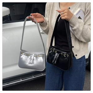 Detail of silver metallic and black patent leather underarm bags with drawstring accents