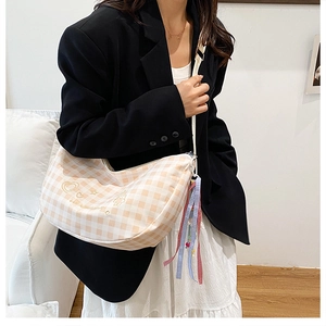 Detail of checkered hobo bag with star embroidery and colorful charms on a model