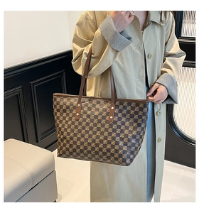 Close-up of retro checkered tote bag with brown straps and vintage metal rivets