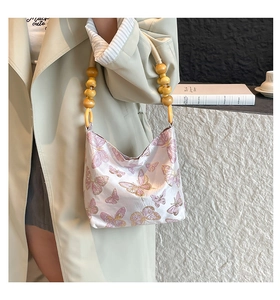 Detail of butterfly embroidery on silk handbag with unique wooden bead handles