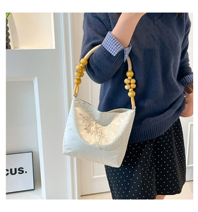Detail of embroidered silk satin fabric with traditional floral pattern and wooden beads