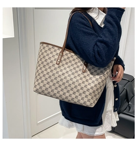 Close-up of vintage large tote bag with monogram pattern on a woman's shoulder