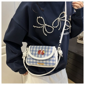 Detailed view of blue and white checkered mini bag with red apple pattern and slim strap