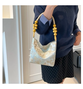 Detail of light blue oriental embroidery bag with gold landscape and wooden bead handle