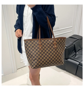 Detail of classic brown checkered tote bag with leather straps on model shoulder