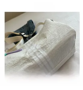 Detail shot of white quilted gym bag featuring parallel stripe texture on denim background