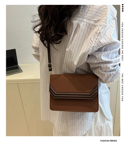Detail of a brown two-tone square shoulder bag with geometric flap layers and strap