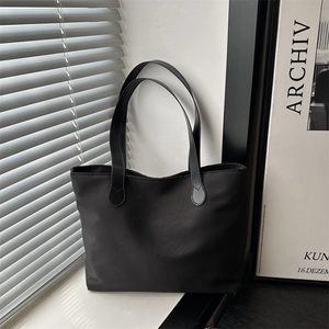 Minimalist black nylon tote bag with teardrop stitch detail on a modern windowsill