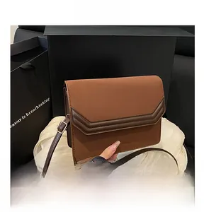 Detail shot of a brown color-block crossbody bag featuring contrast leather trim and flap