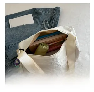 Top view of white crossbody pillow bag showing large capacity with umbrella and books inside