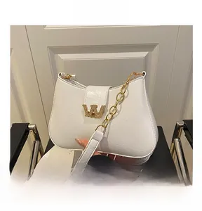 Dettaglio borsa in pelle bianca con logo W dorato con diamanti e tracolla a catena in oro