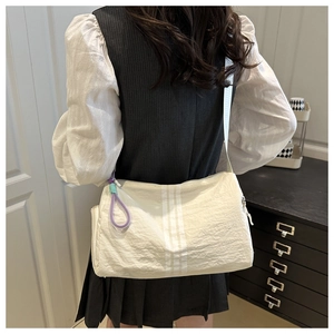 Detail of a cream Oxford cloth crossbody bag with triple stripes and purple zipper cord
