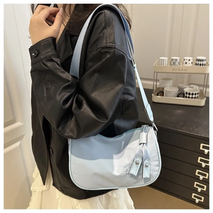 Close-up of light blue nylon hobo bag with CH embroidery and long zipper ribbons