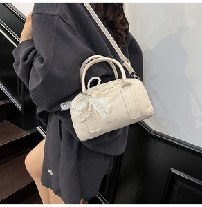 Détail du sac Boston en cuir PU blanc crème avec chaîne de perles et nœud en dentelle