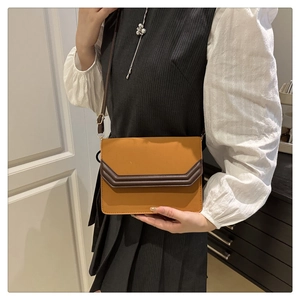 Model wearing yellow and brown square crossbody bag with V-shaped patchwork design