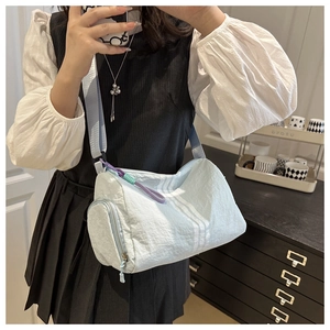 Detail of light blue striped cylinder bag with adjustable strap and contrast zippers