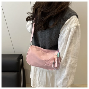 Detail view of pink nylon crossbody pillow bag with CHOU DON embroidery on woman shoulder