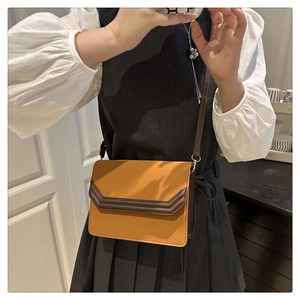 Detail view of mustard yellow suede patchwork crossbody bag with brown trim on model