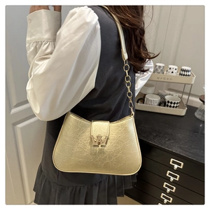 Dettaglio borsa hobo dorata con fibbia a W di diamanti e tracolla a catena