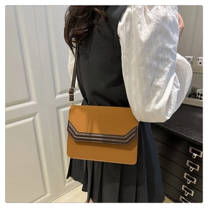 Détail d'un sac bandoulière vintage moutarde et marron porté par un mannequin en vue réelle