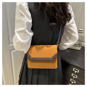 Détail d'un sac bandoulière carré moutarde avec des coutures brunes élégantes